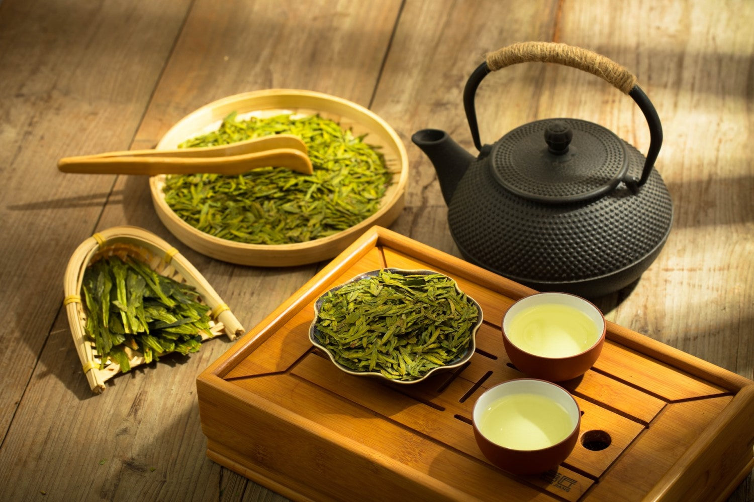 Green tea in a teapot alongside 2 cups with green tea